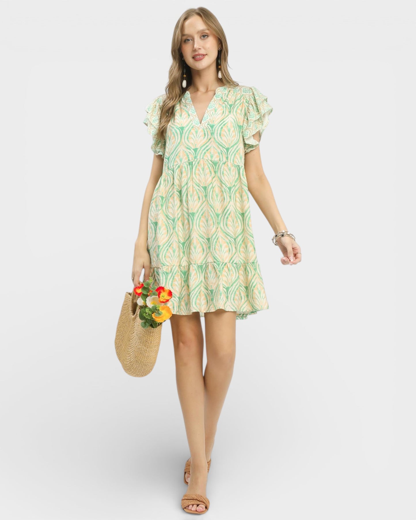 Woman wearing a floral dress holding flowers against a white background