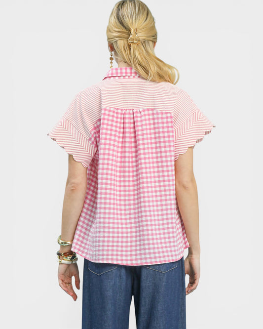 Person wearing a pink and white checkered shirt with short sleeves on a plain background