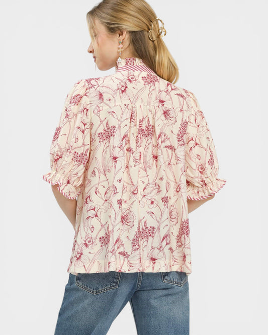 Woman wearing a floral blouse with puffed sleeves on a white background