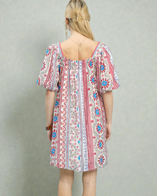 Woman wearing a colorful patterned dress against a plain background