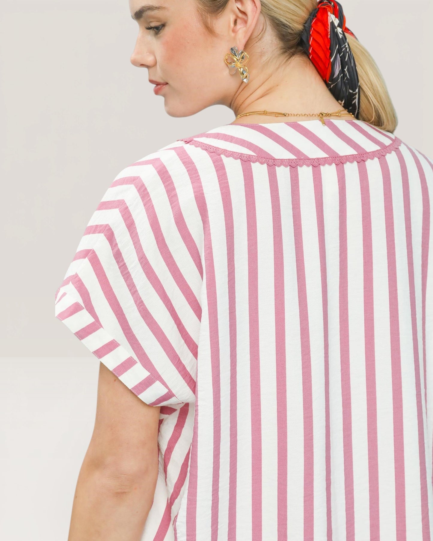 Woman wearing a pink and white striped shirt against a plain background