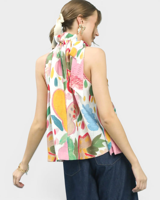 Woman wearing a colorful sleeveless top with floral pattern on a white background
