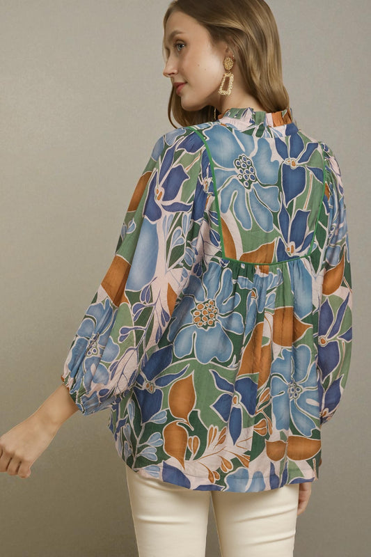 Woman wearing a colorful floral blouse against a neutral background