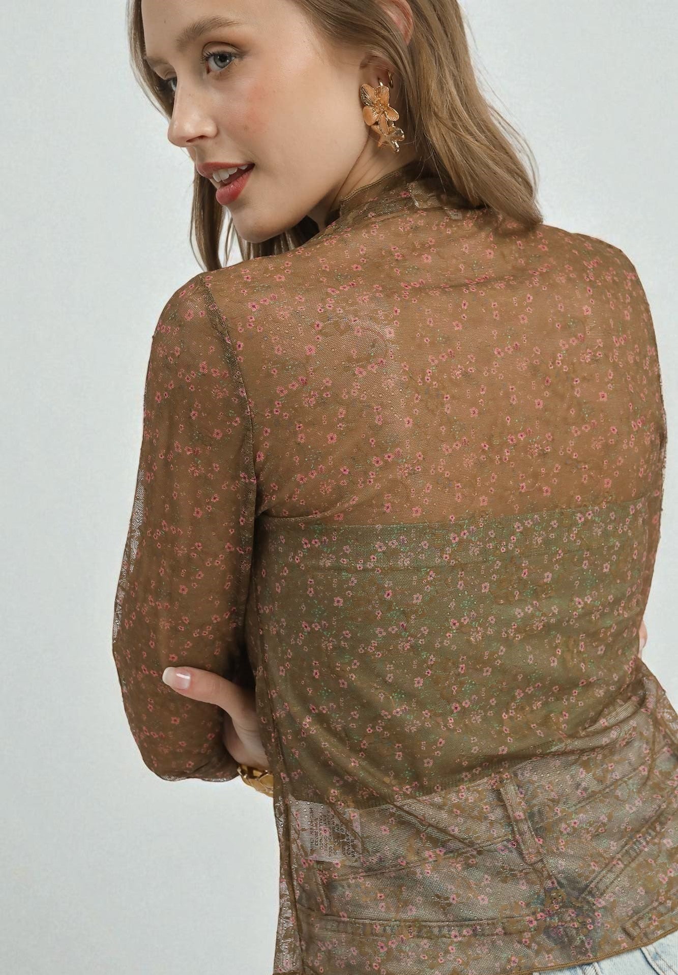 Woman wearing a brown patterned blouse on a white background