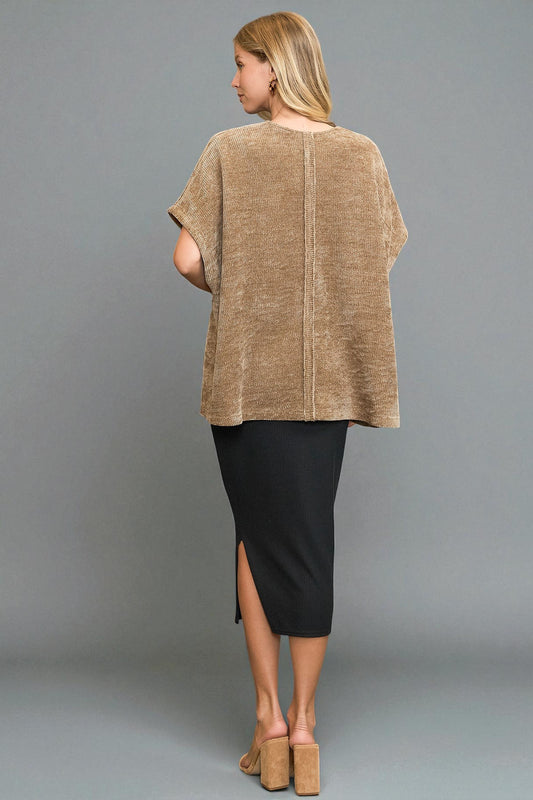 Woman wearing a beige top and black skirt against a gray background