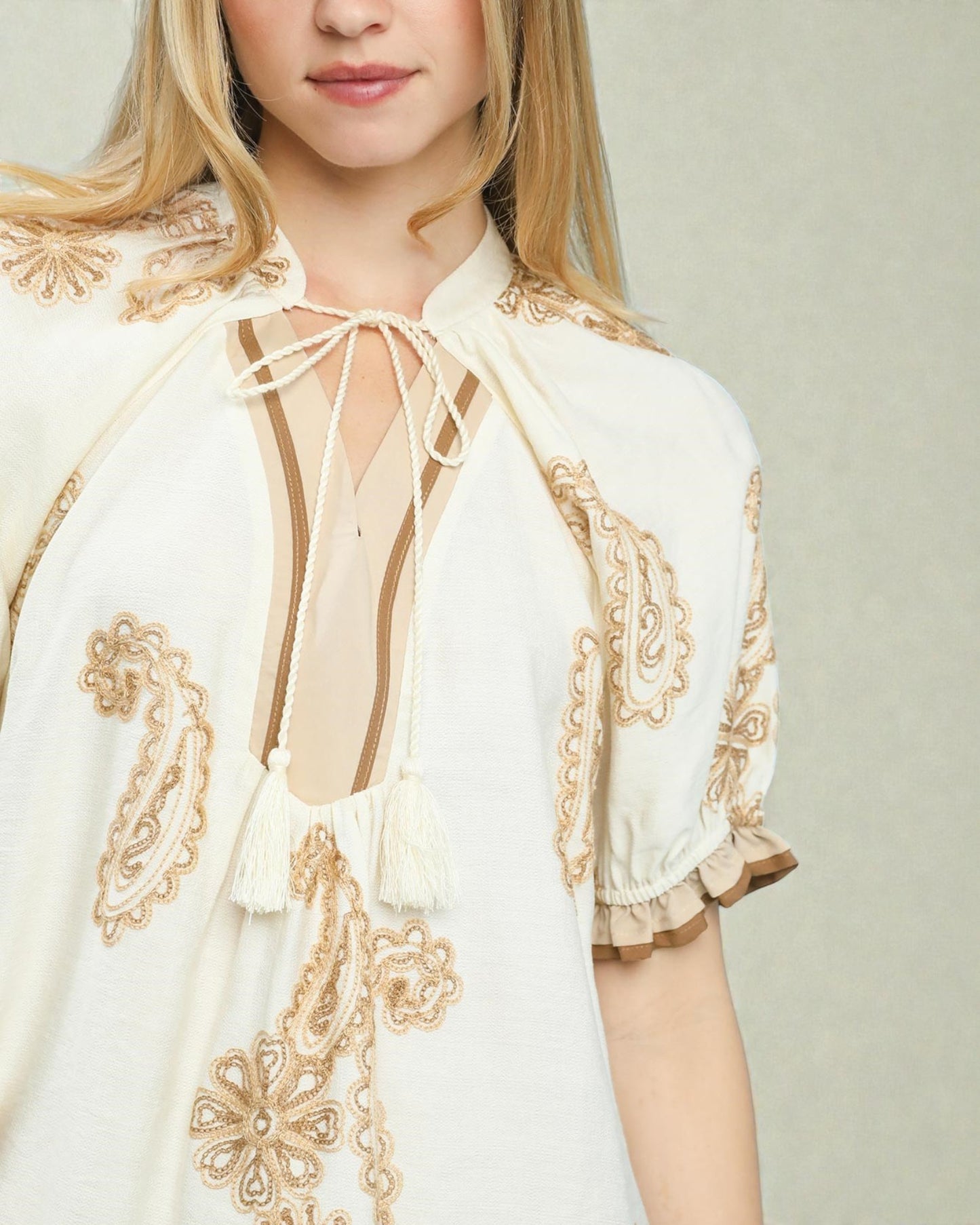 White blouse with gold embroidery on a plain background