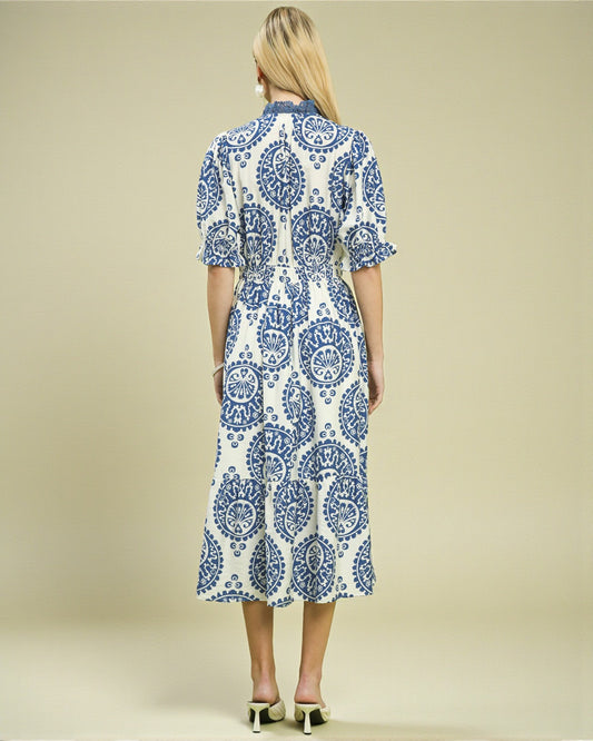 Woman wearing a blue and white patterned dress on a beige background