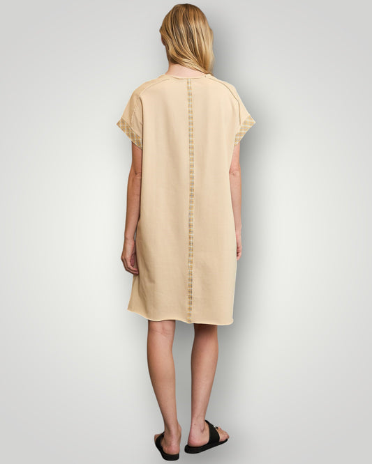 Woman wearing a beige dress with a plain background