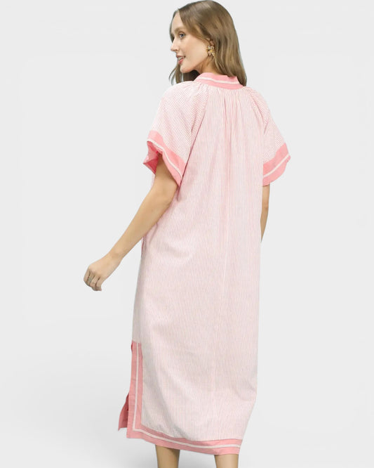 Woman wearing a pink dress with white stripes on a plain background