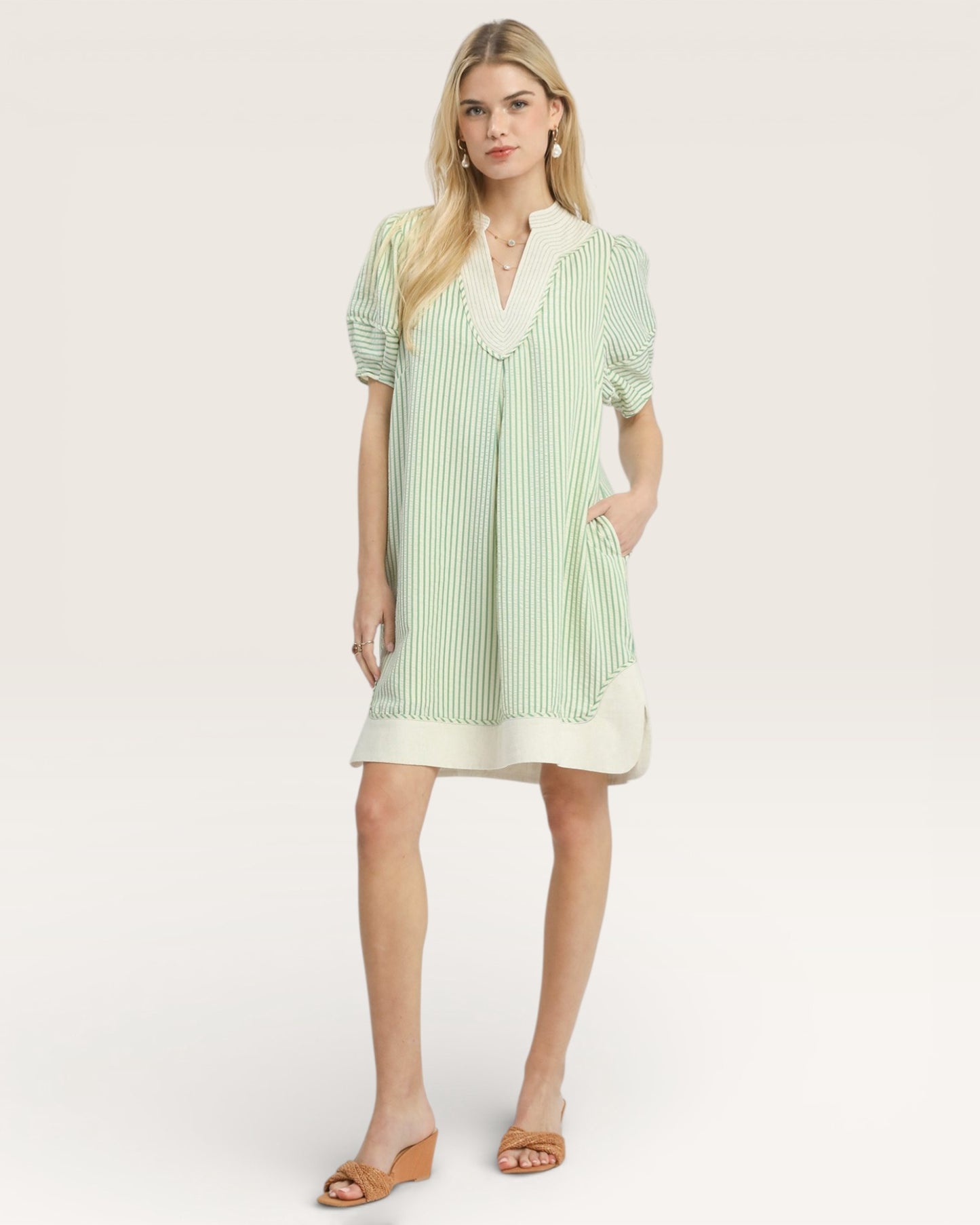 Woman wearing a green and white striped dress on a white background