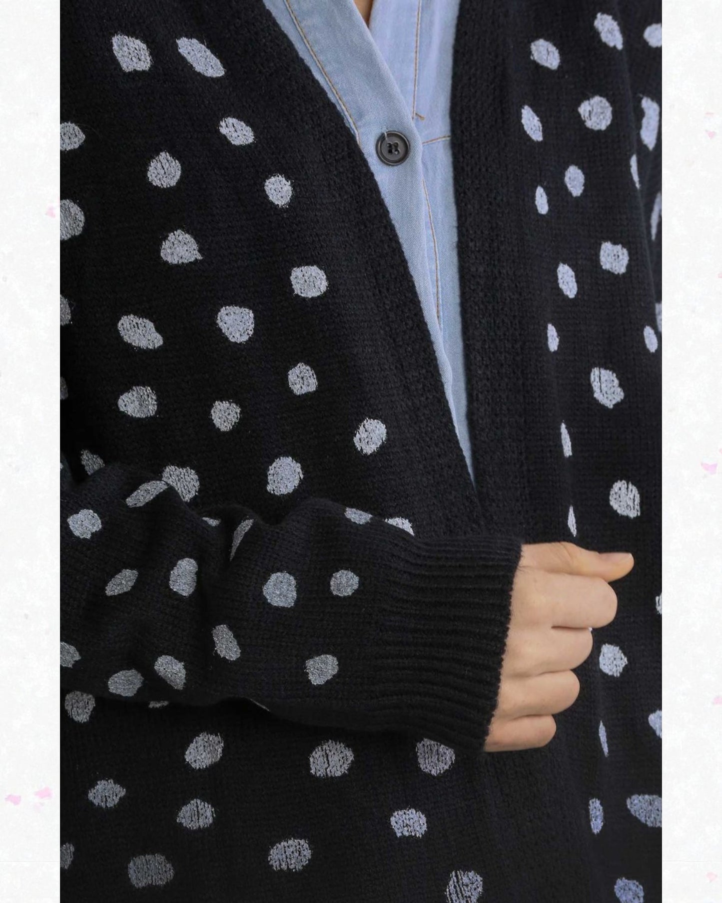 Black cardigan with white polka dots worn over a light blue shirt.