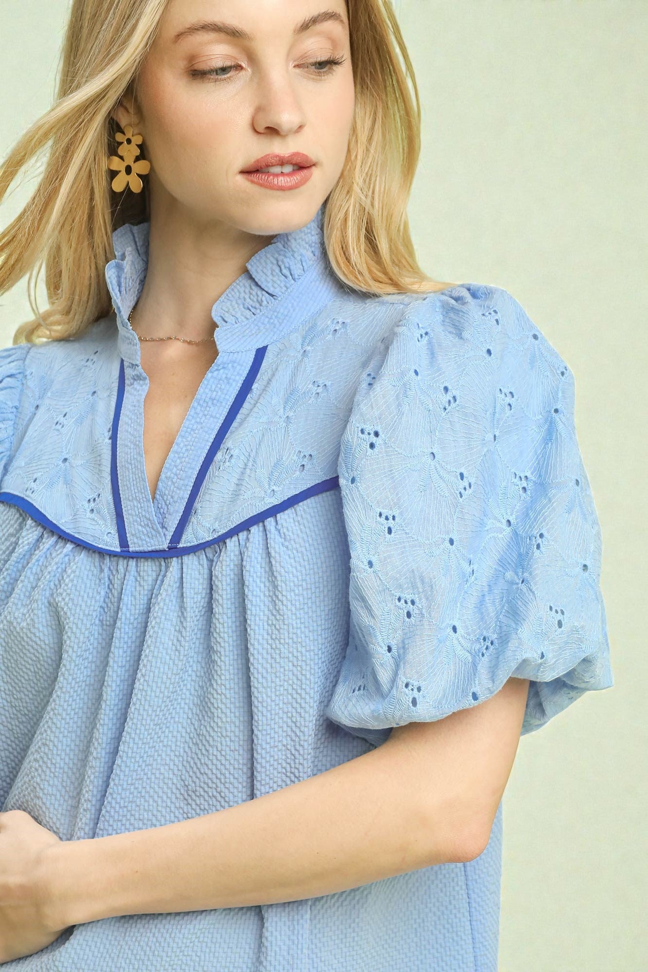 Woman wearing a light blue dress with a subtle pattern on a plain background