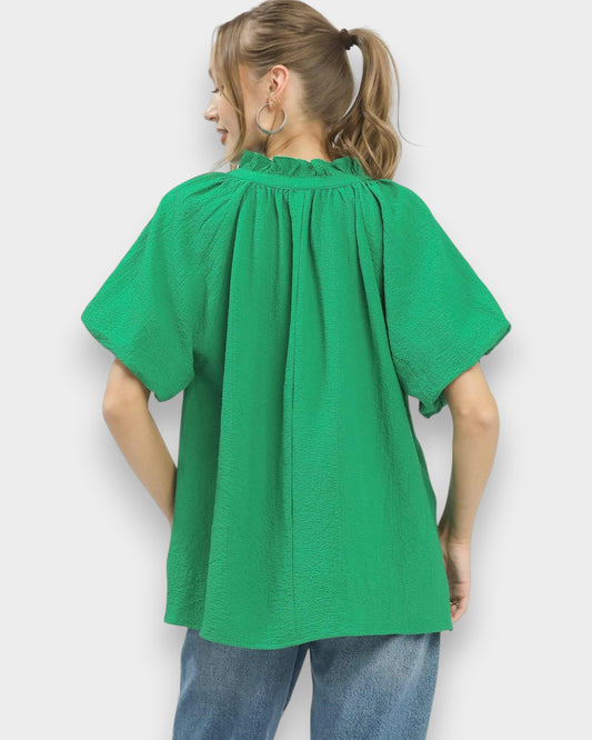 Person wearing a green blouse with short sleeves against a white background