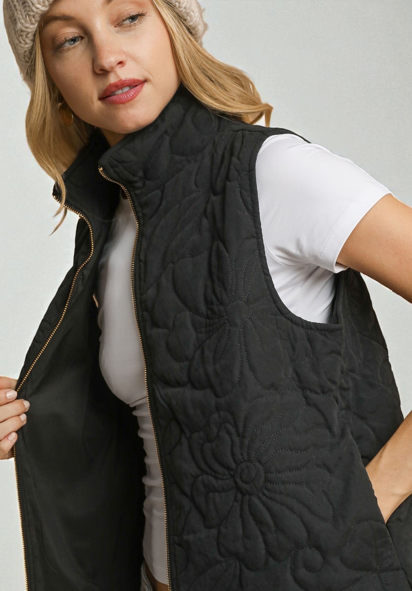 Woman wearing a black quilted vest on a plain background