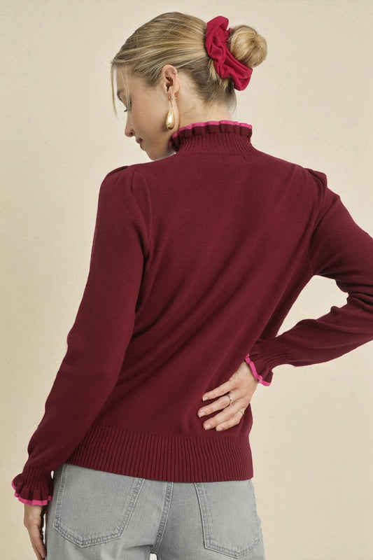 Woman wearing a burgundy sweater with a plain background