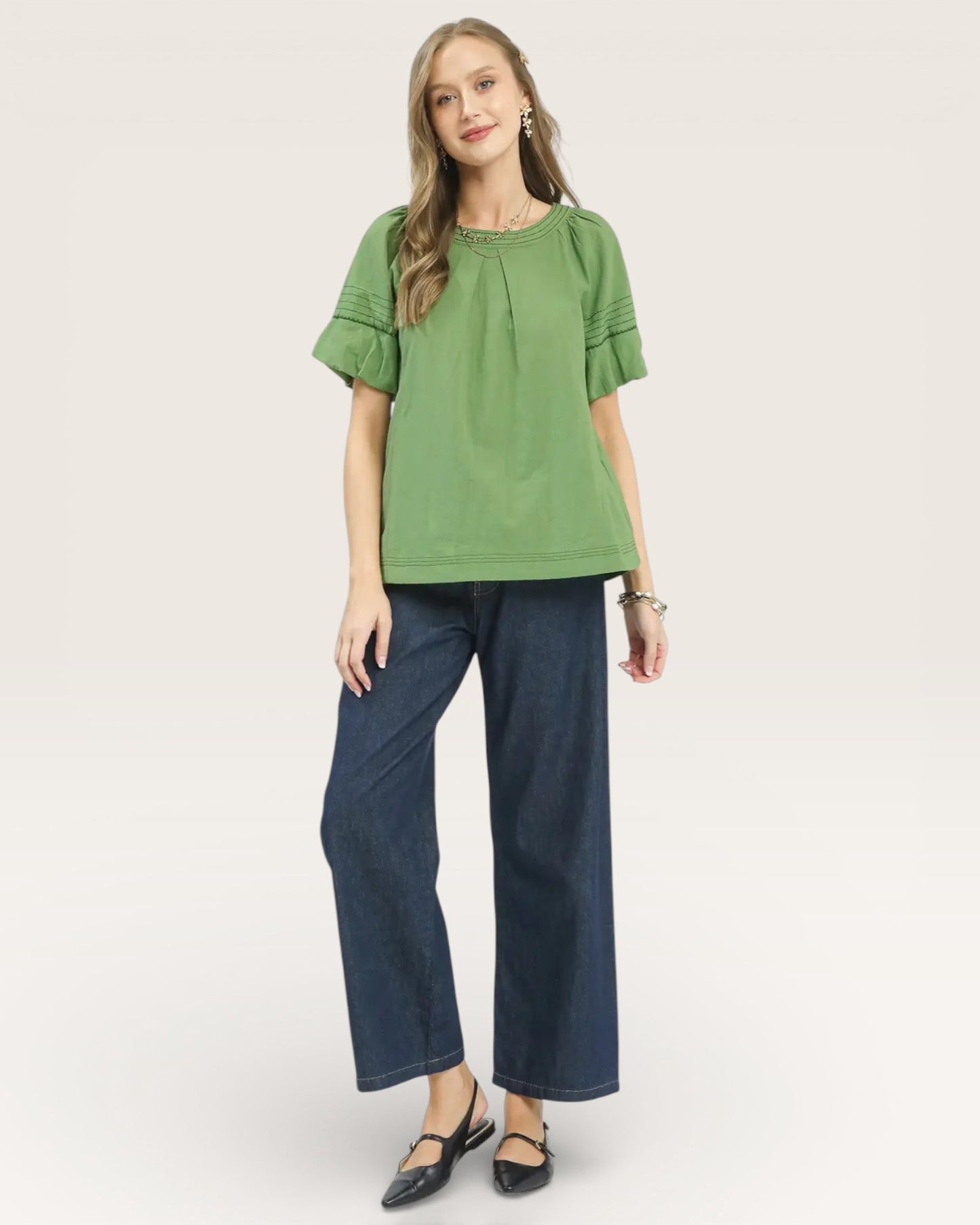 Woman wearing a green blouse and blue pants on a white background