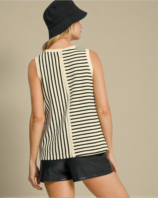 Woman wearing a black and white striped sleeveless top with a black hat and shorts on a beige background