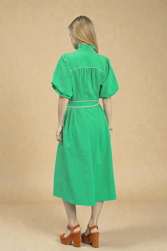 Woman wearing a green dress with white embroidery on a beige background