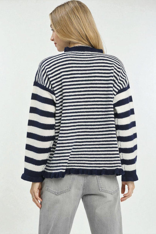 Woman wearing a navy and white striped sweater on a plain background