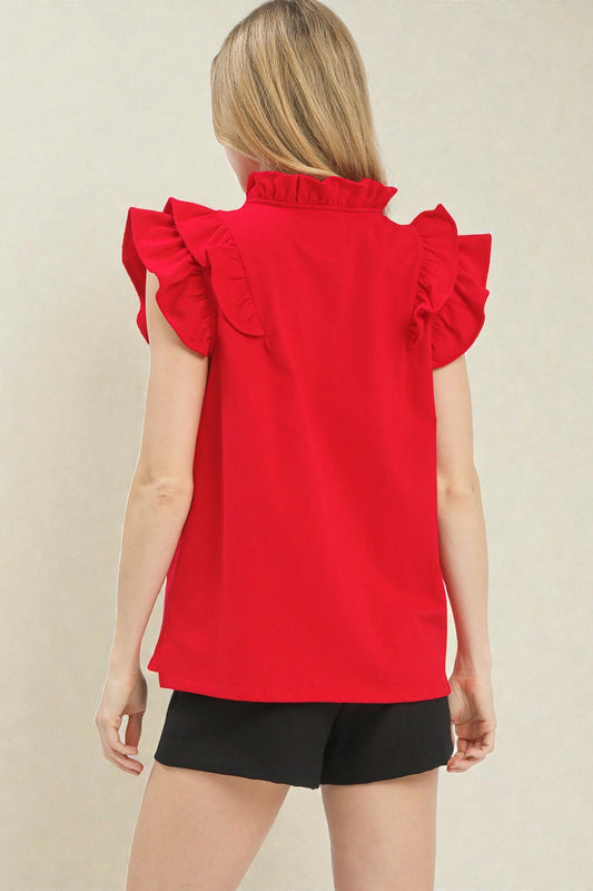 Red sleeveless top with ruffled shoulders worn by a person on a beige background