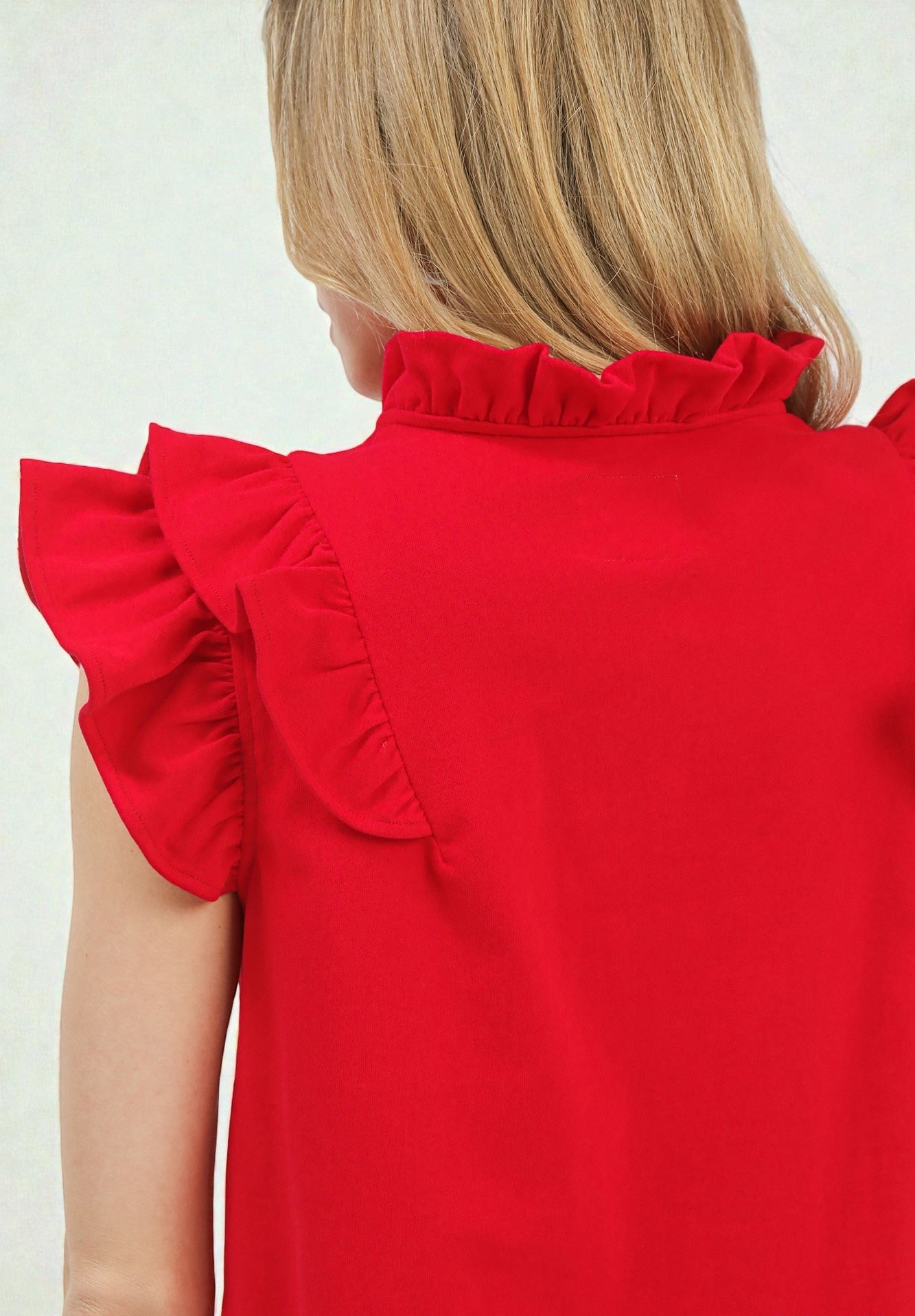 Red blouse with ruffled shoulders on a plain background
