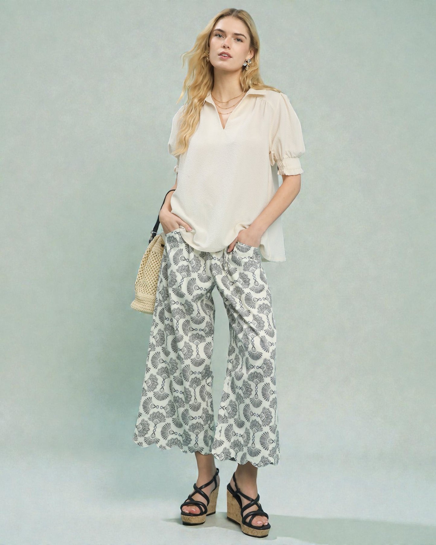 Woman wearing a white blouse and patterned pants with a neutral background
