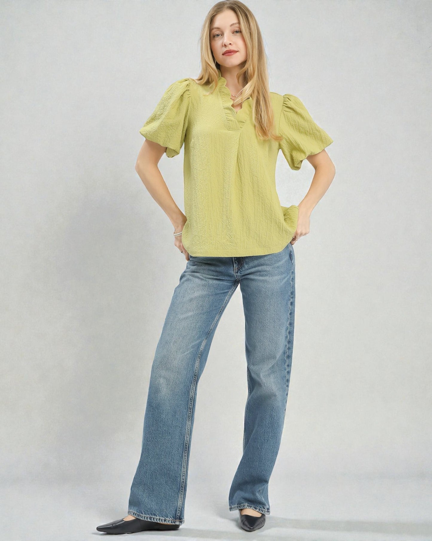 Woman wearing a green blouse and blue jeans on a white background