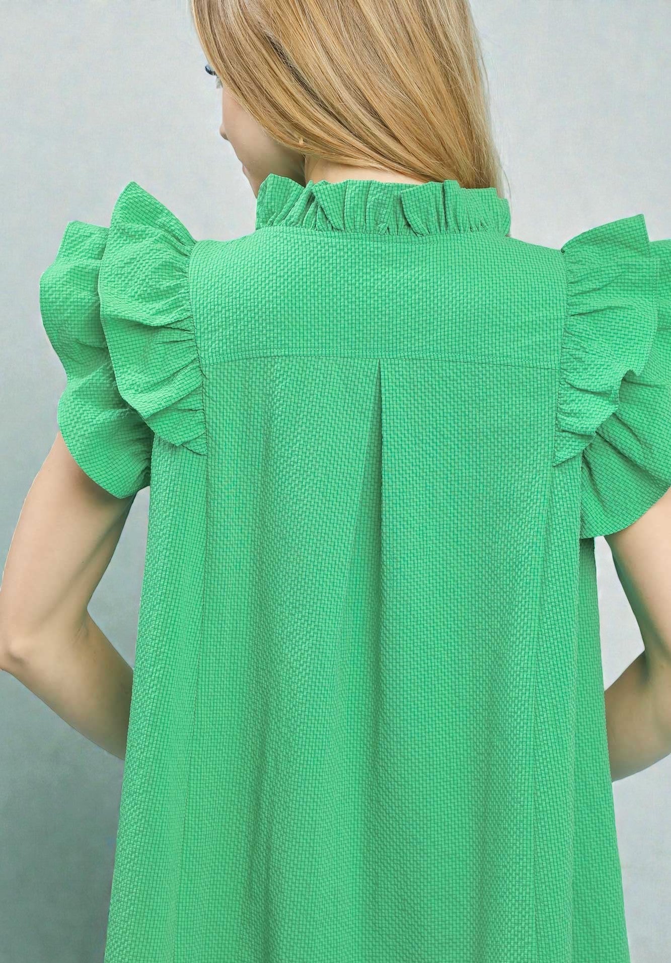 Green dress with ruffled sleeves on a plain background