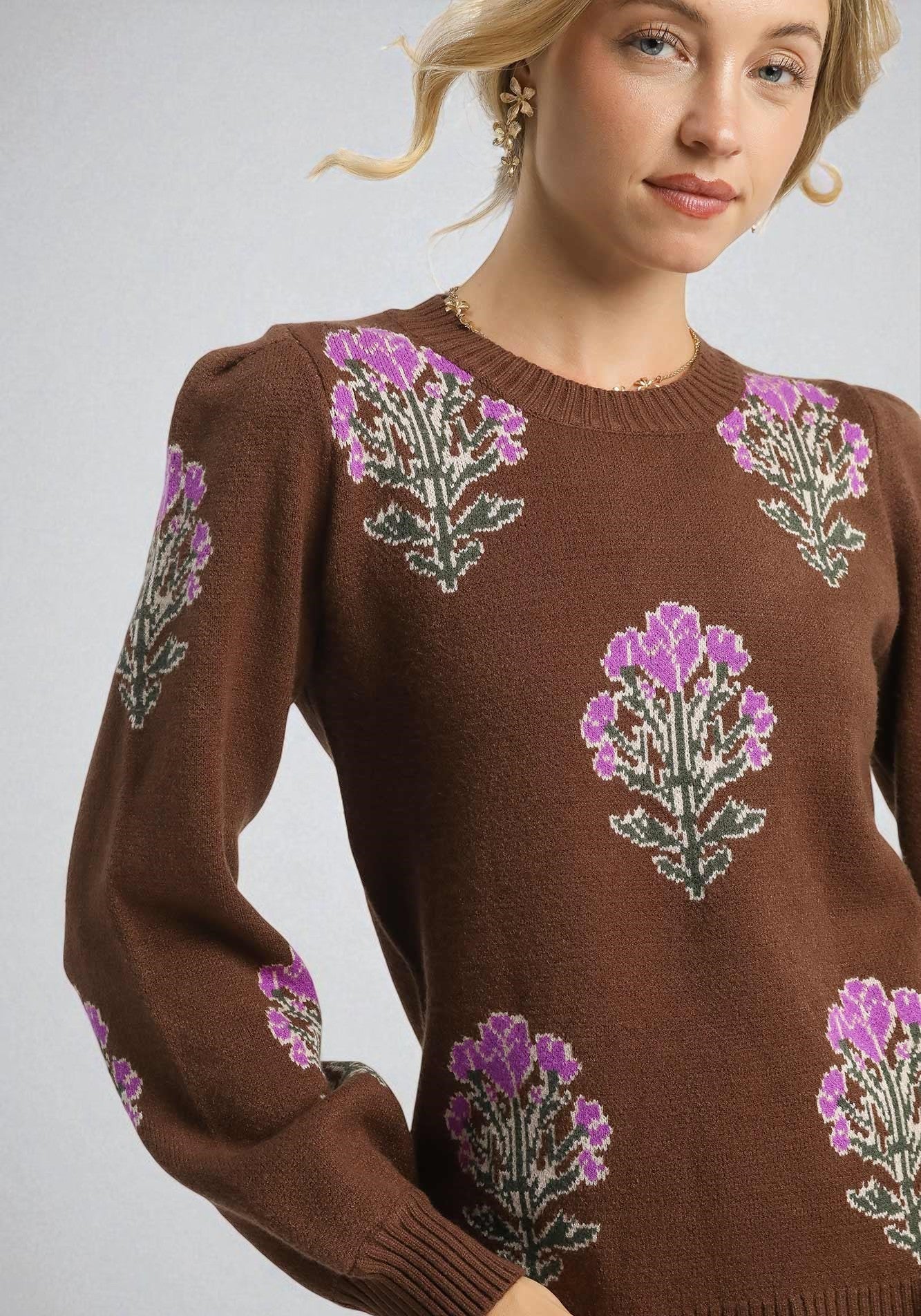 Woman wearing a brown sweater with floral patterns on a gray background