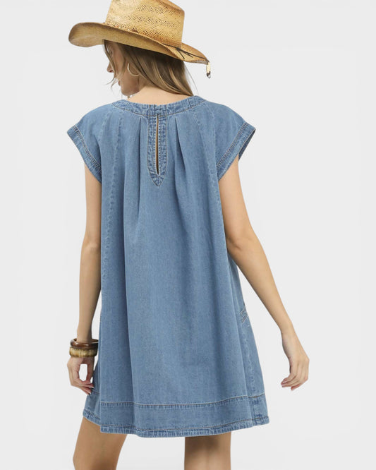 Woman wearing a blue denim dress and straw hat on a white background