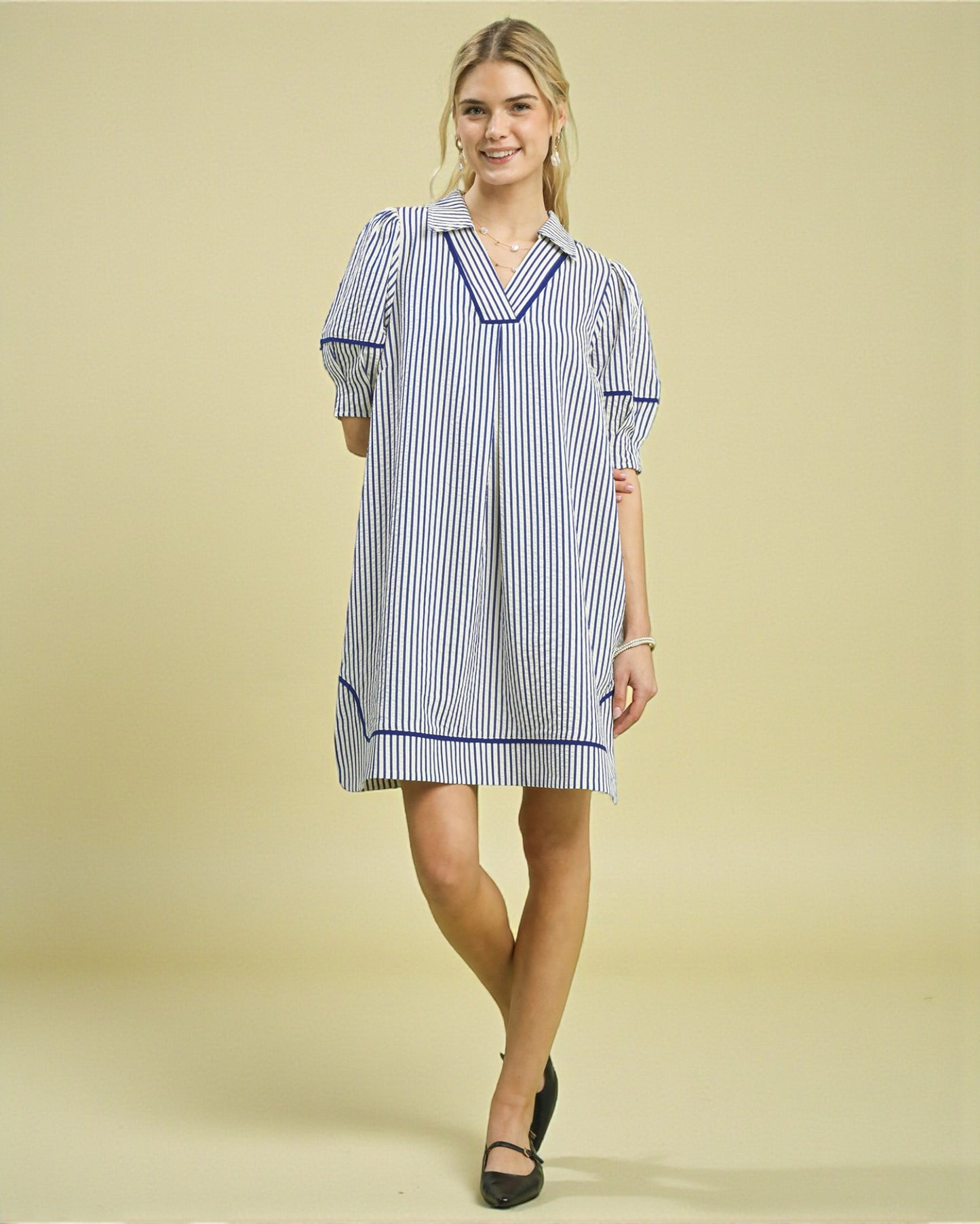 Woman wearing a blue and white striped dress against a beige background