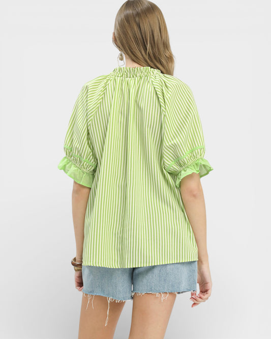Person wearing a green striped shirt and denim shorts on a white background