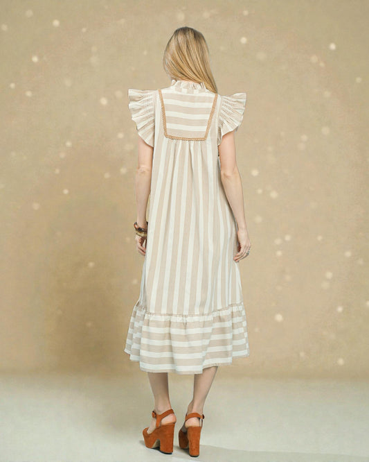 Woman wearing a white dress with ruffled sleeves against a beige background