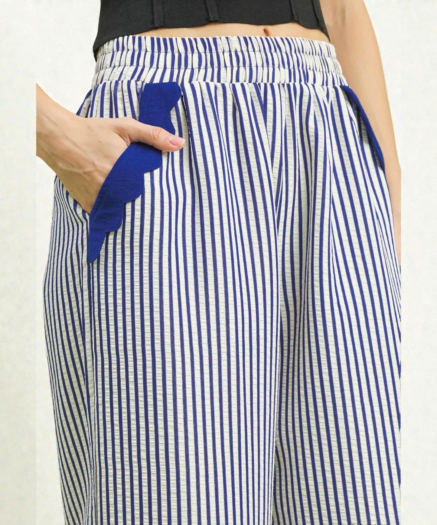 Blue and white striped pants with a blue towel in a pocket on a plain background