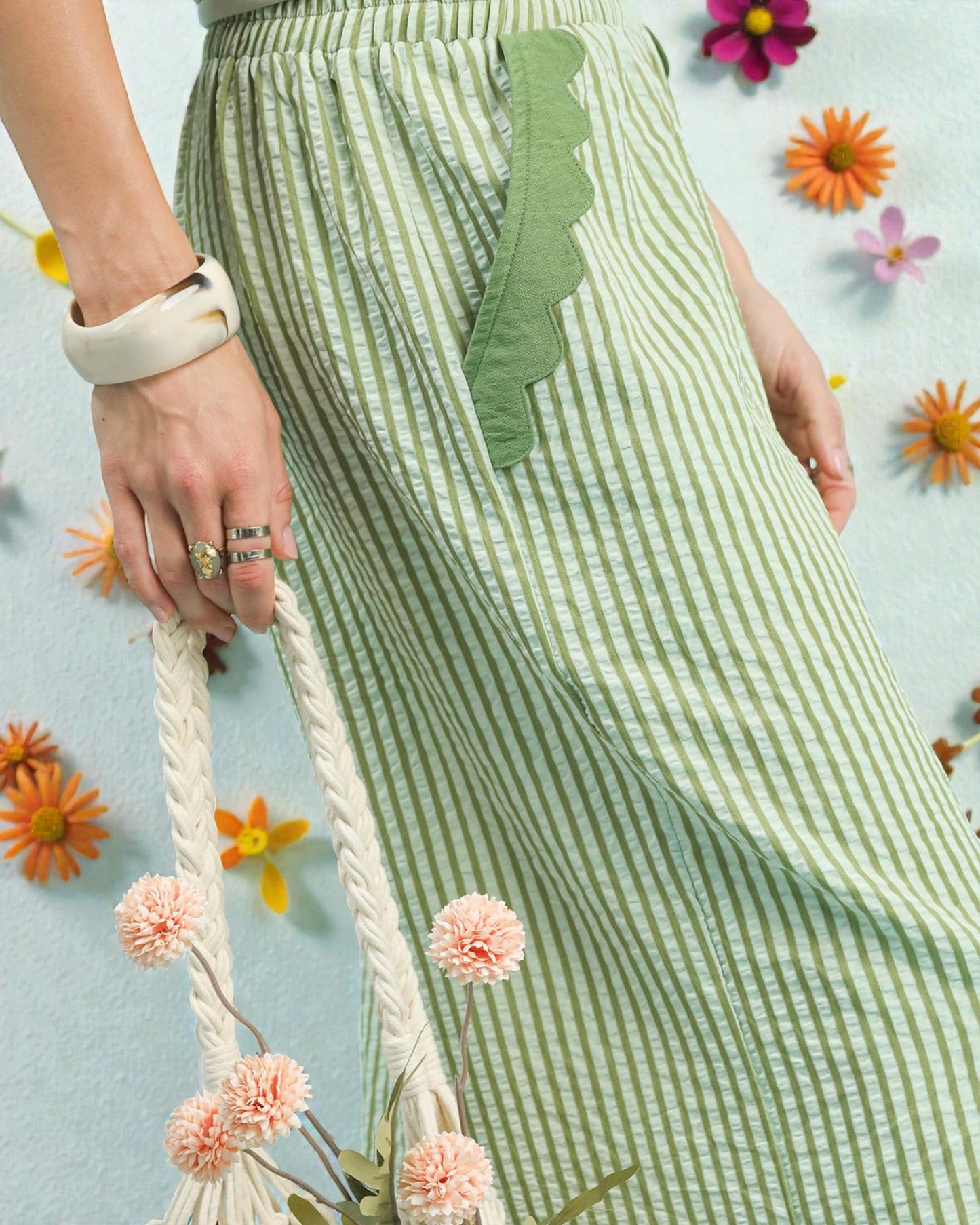 Green and white striped skirt with a decorative leaf detail, held by a person against a floral background.