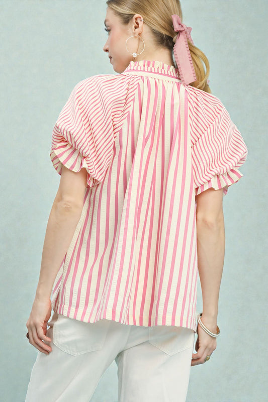 Woman wearing a pink and white striped blouse against a light gray background