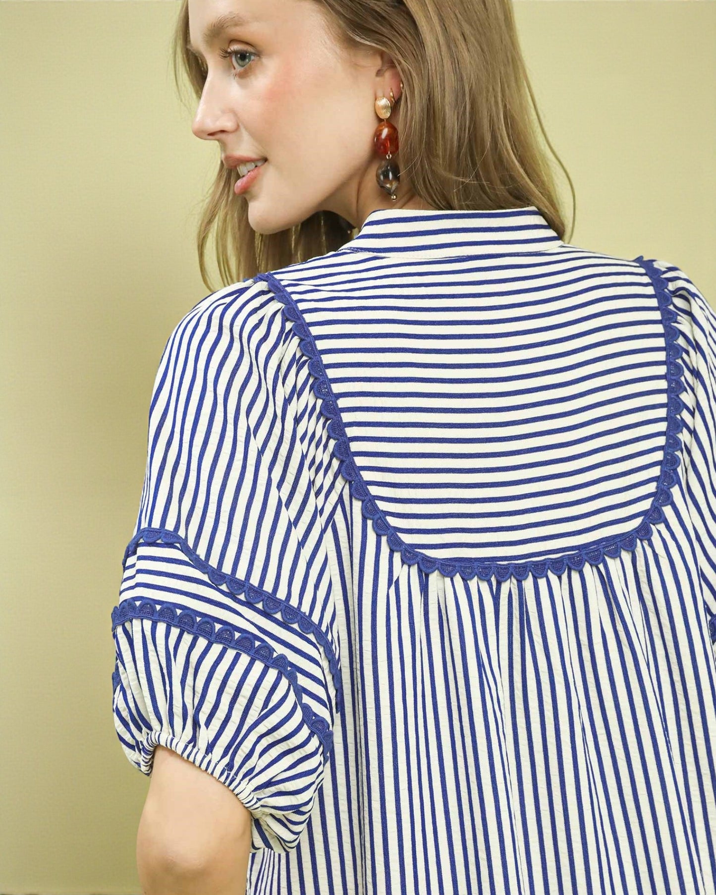 Woman wearing a blue and white striped shirt with a beige background