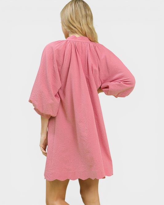 Person wearing a pink textured dress on a white background