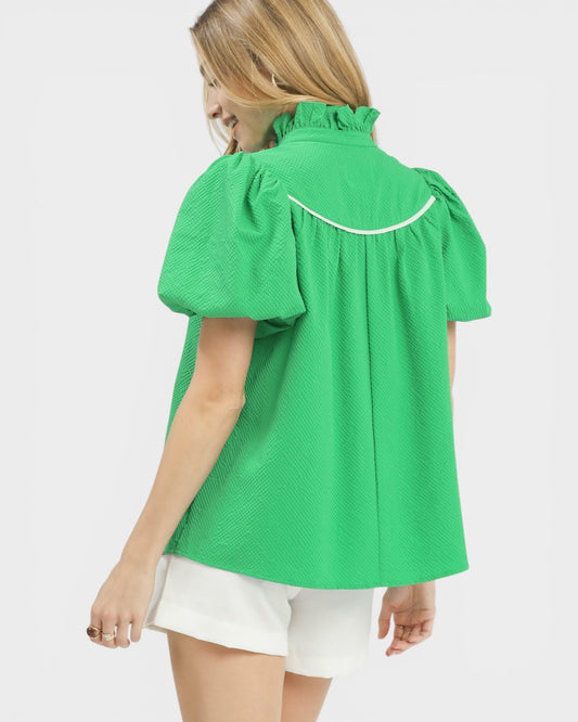 Woman wearing a green blouse with white trim on a white background