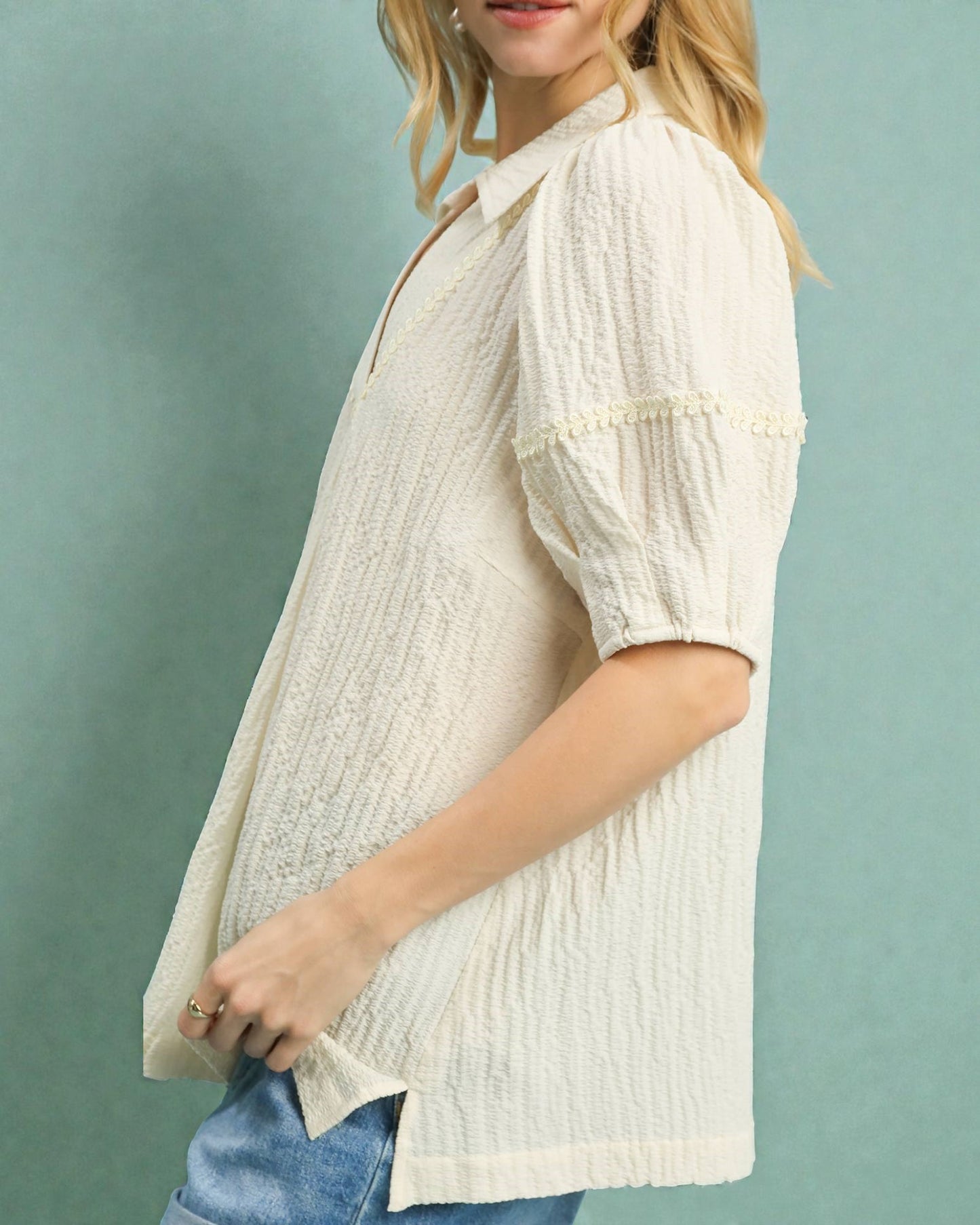 Woman wearing a white textured blouse with short sleeves against a light blue background