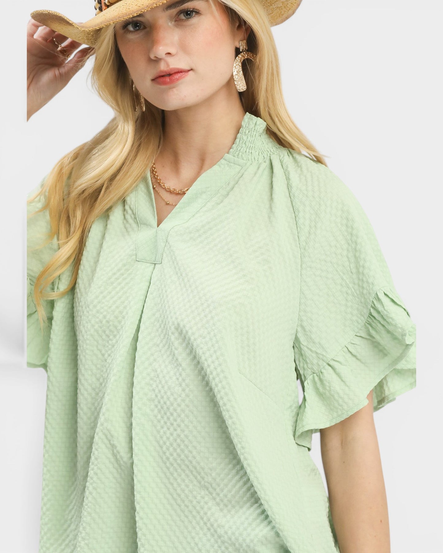 Woman wearing a light green textured dress with a white background