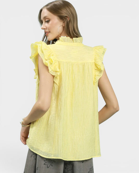Woman wearing a yellow blouse with ruffled sleeves on a white background