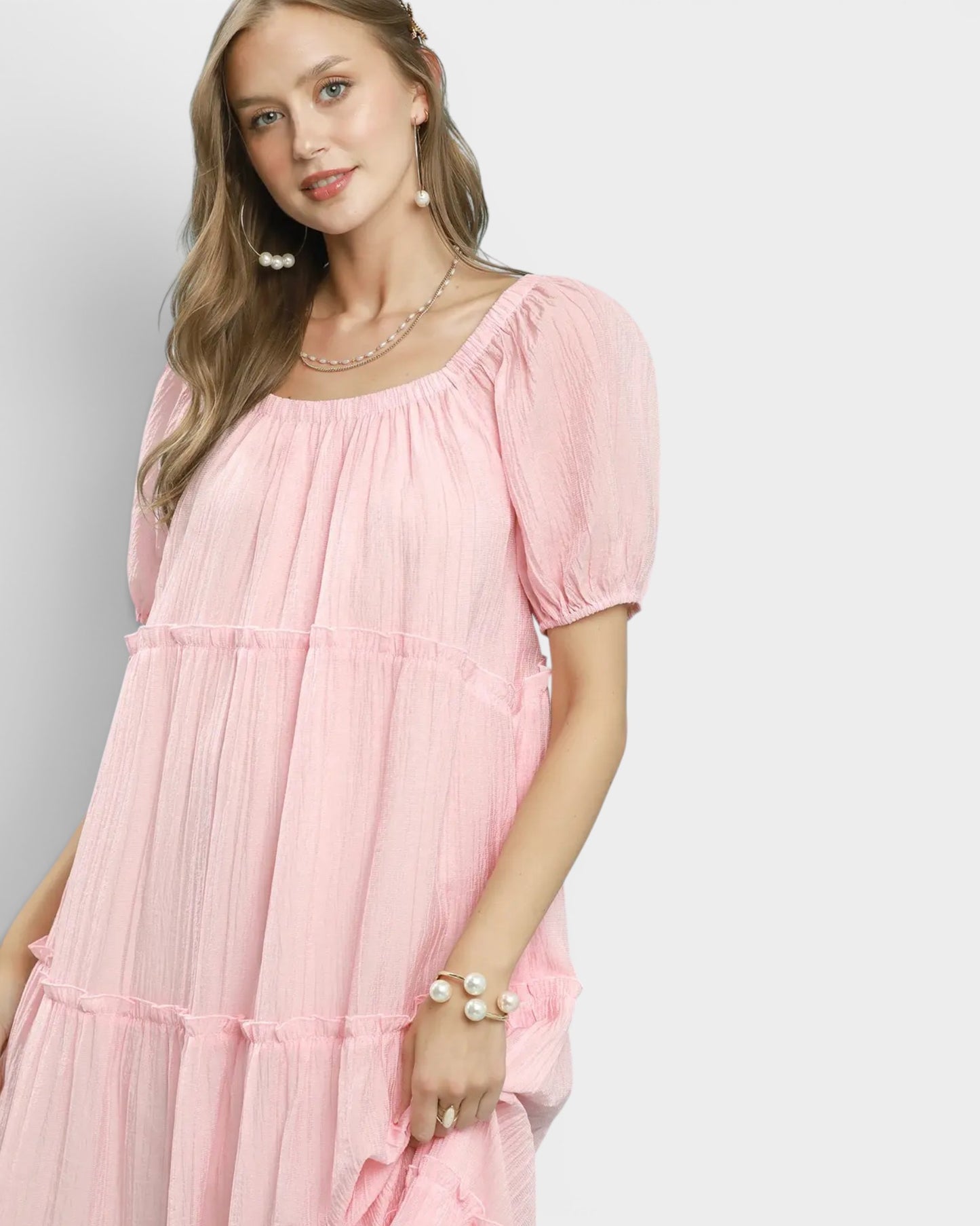 Woman wearing a pink dress with puffed sleeves on a light gray background