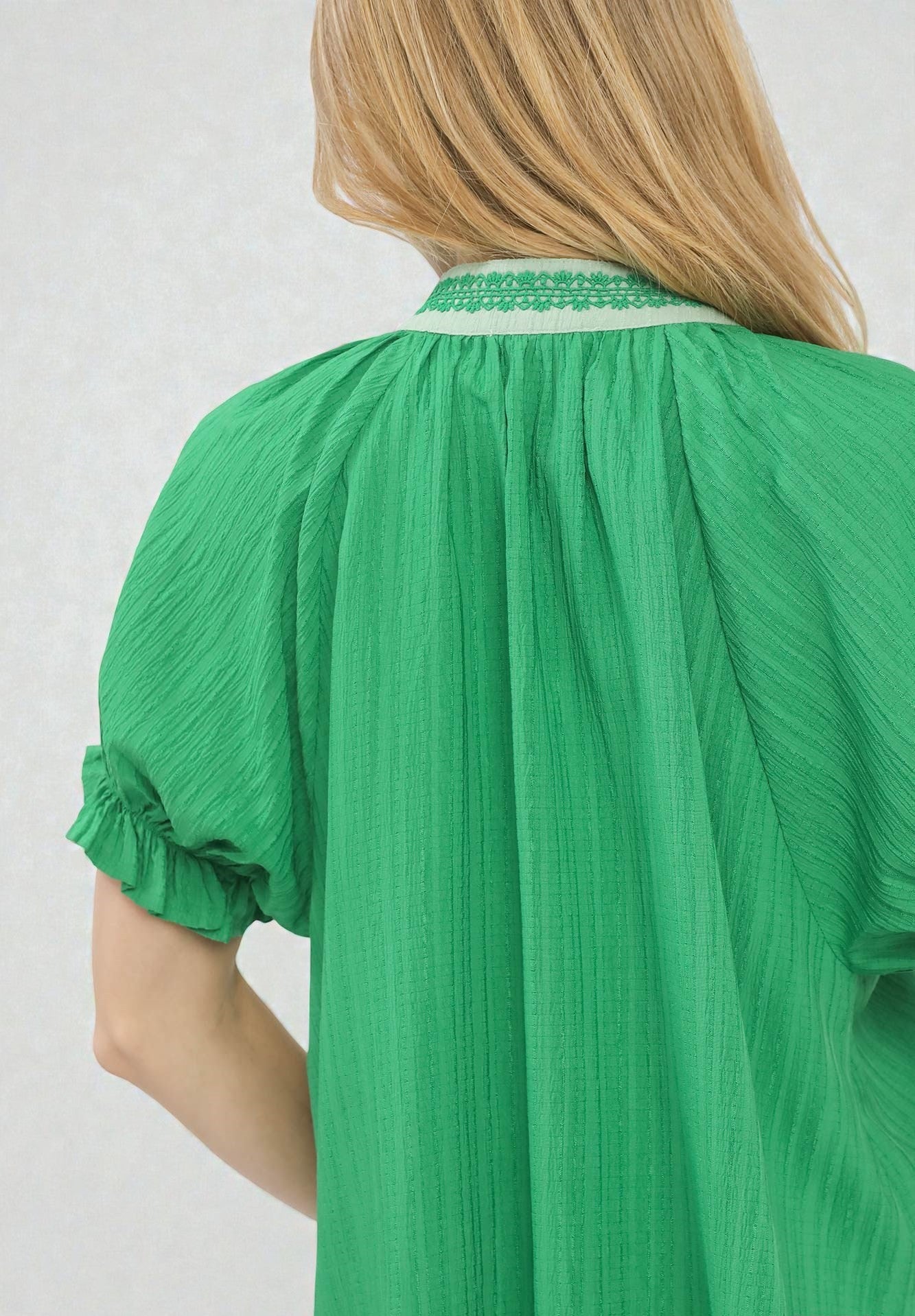 Green dress with ruffled sleeves on a plain background