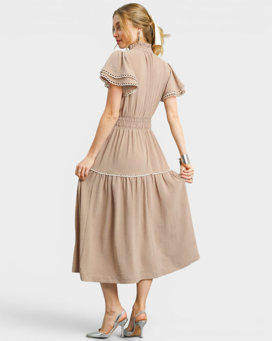 Woman wearing a beige dress with ruffled sleeves on a white background
