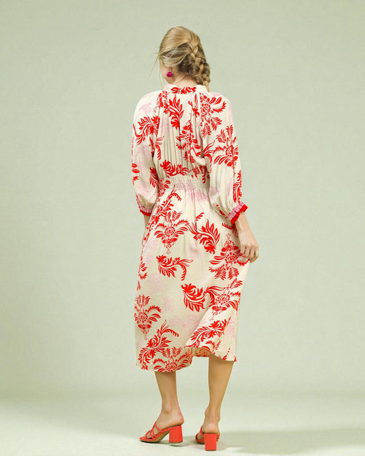 Woman wearing a white dress with red floral pattern on a plain background
