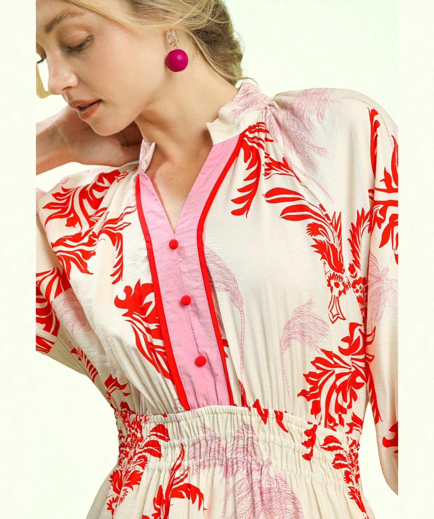 Woman wearing a dress with red floral patterns and pink accents.