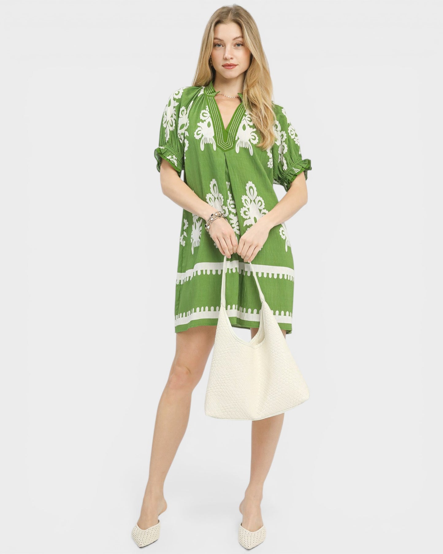 Woman wearing a green dress with white patterns on a white background
