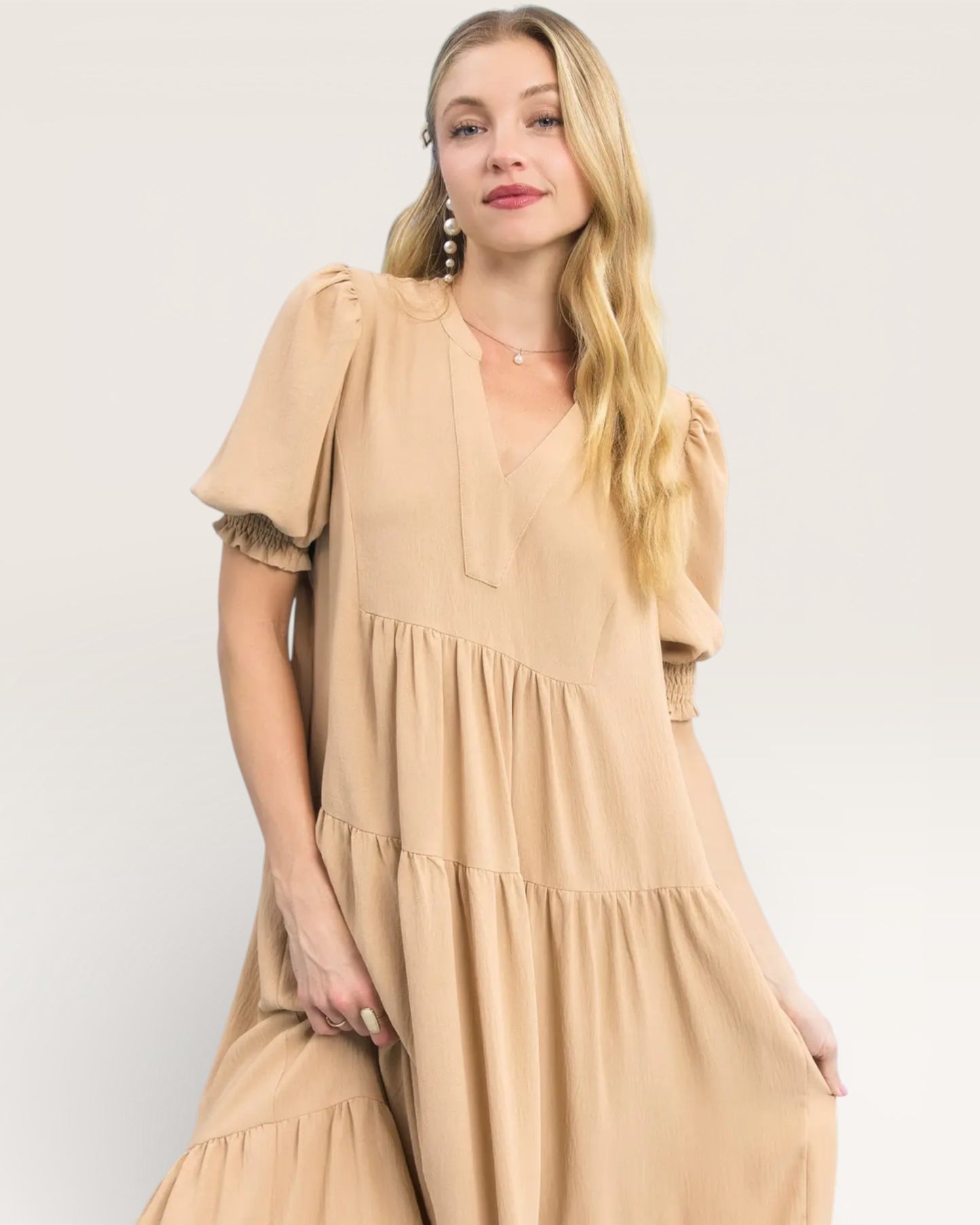 Woman wearing a beige dress against a white background