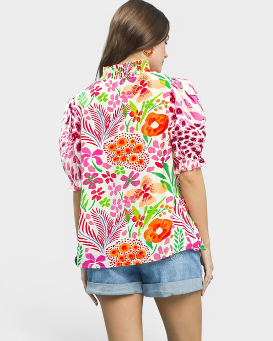 Woman wearing a colorful floral blouse with denim shorts on a white background